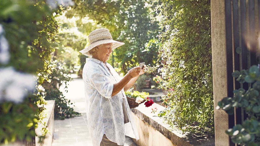 Mujer mayor recogiendo flores en el jardín